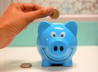 person putting coin in a piggy bank